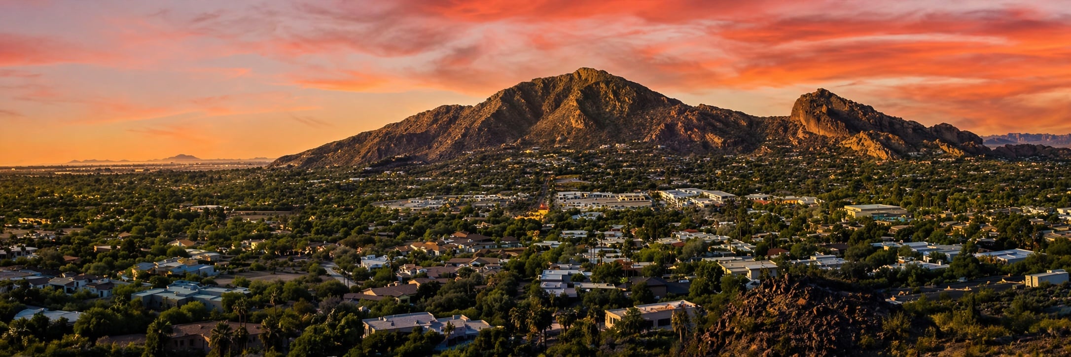 Aerial view of Camelback Mountain at golden hour with Paradise Valley luxury neighborhoods below.